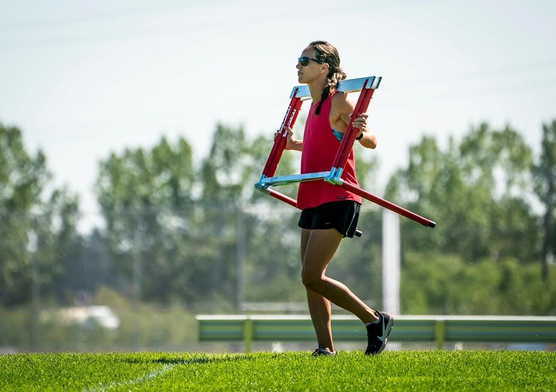 Jessica Zelinka carryies track and field hurdles for her team.