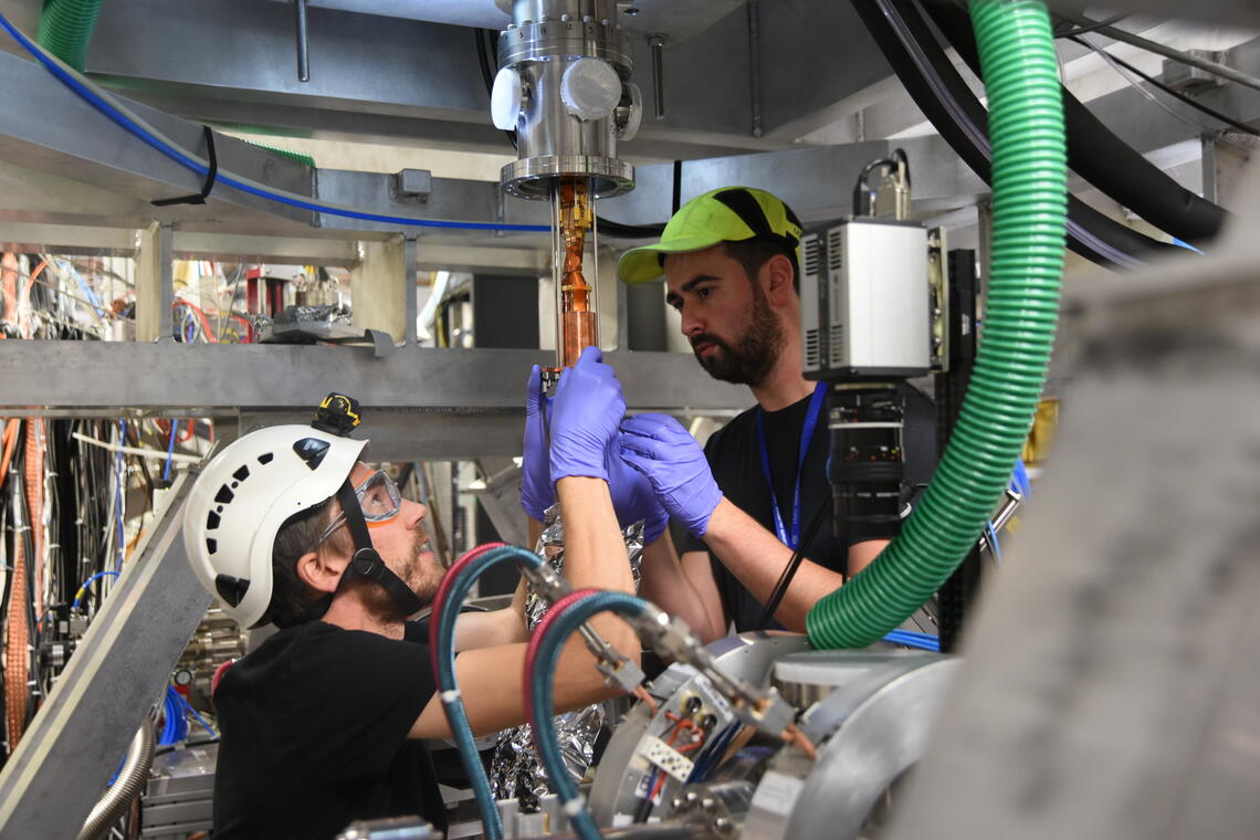 Timothy Friesen and UCalgary PhD student Adam Powell install a Penning trap - a charged particle trap for making antihydrogen atoms- into the ALPHA-g apparatus at CERN.