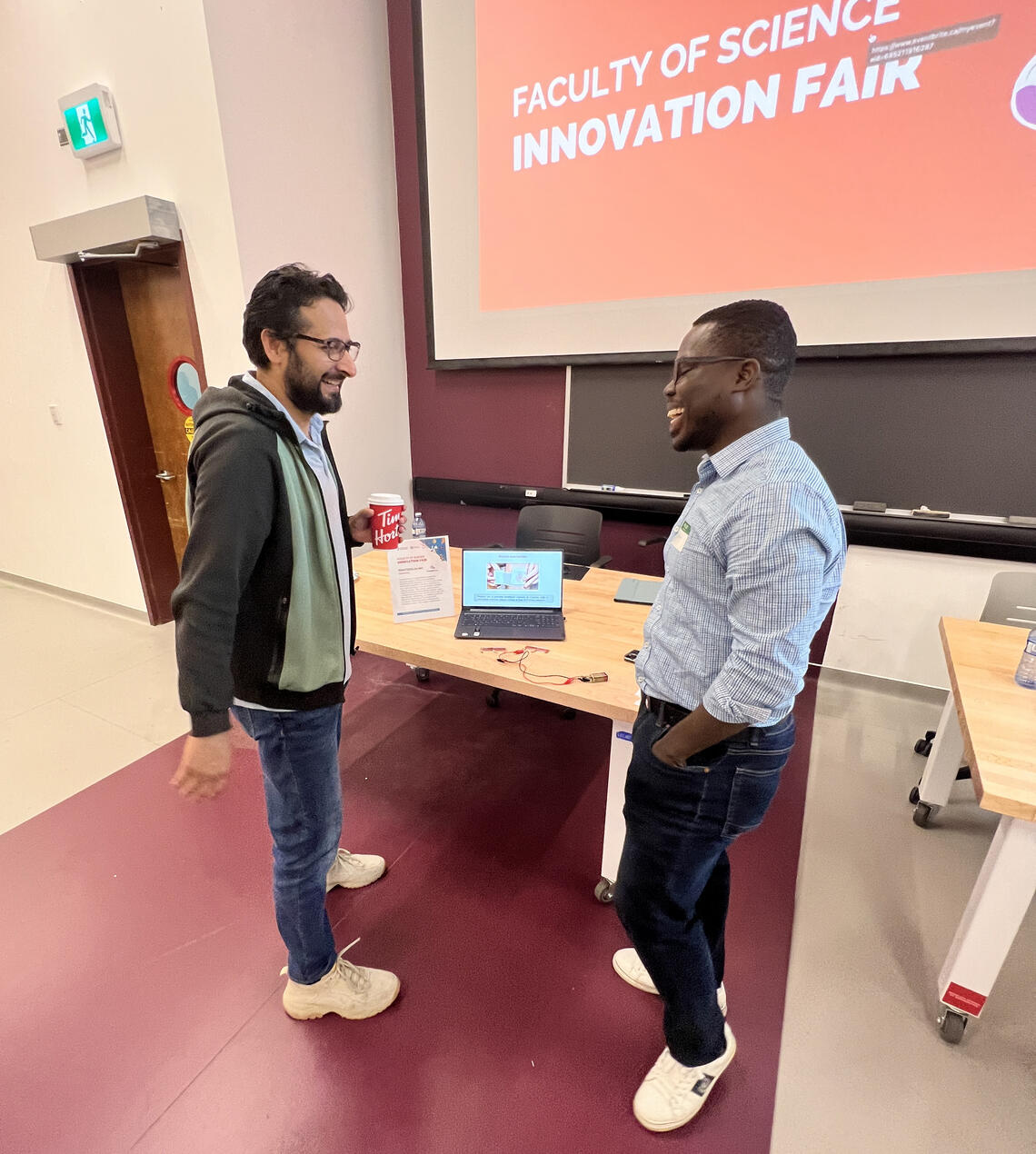 Akpeko Gasonoo, postdoctoral associate in chemistry from PrintedSUN Inc. chats to Dr. Qasim Khan at the Innovation Fair.