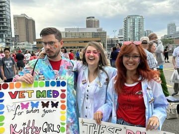 Three veterinary students holding posters at the Pride March