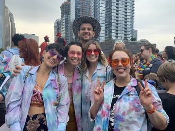 Five veterinary students pose for a photo wearing tie-dye lab coats at the Pride Parade.